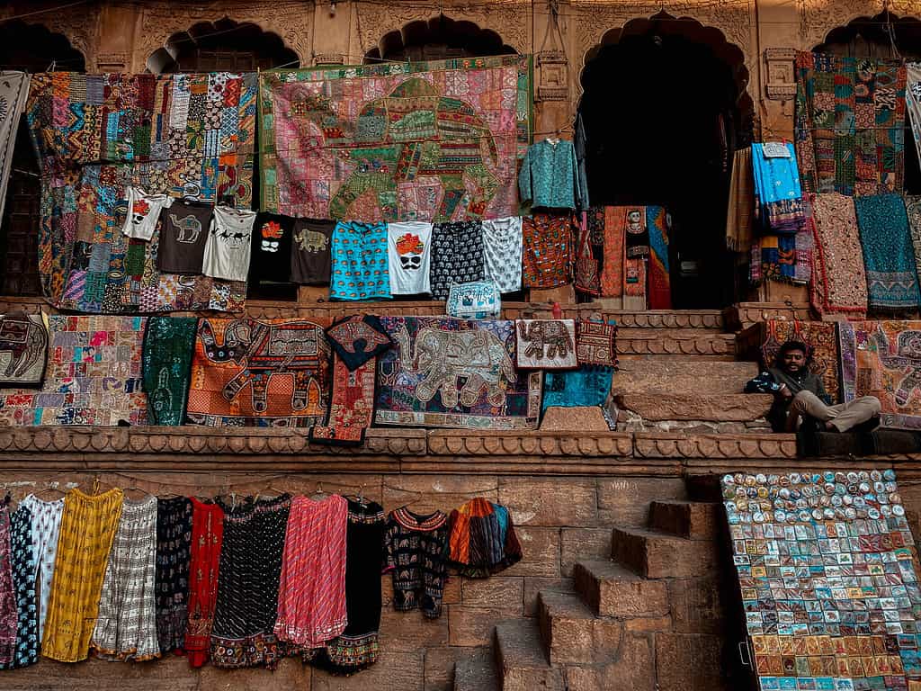 colorful carpets and dresses hung on a wall inside of the Jaisalmer Fort