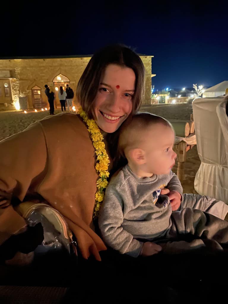 mother wearing a yellow flower necklace with small child on lap during night