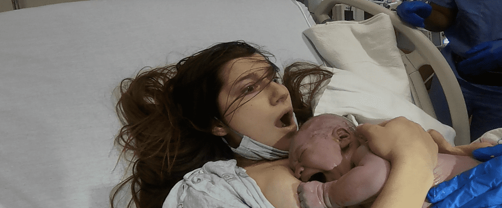 shocked mother with mouth wide open who just give birth when baby is laid on her chest seconds after birth
