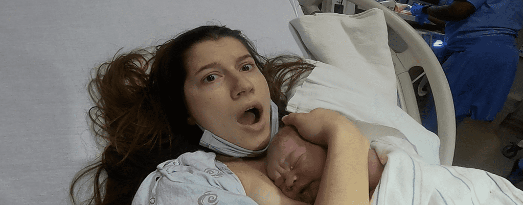 shocked mother with mouth wide open who just give birth when baby is laid on her chest seconds after birth