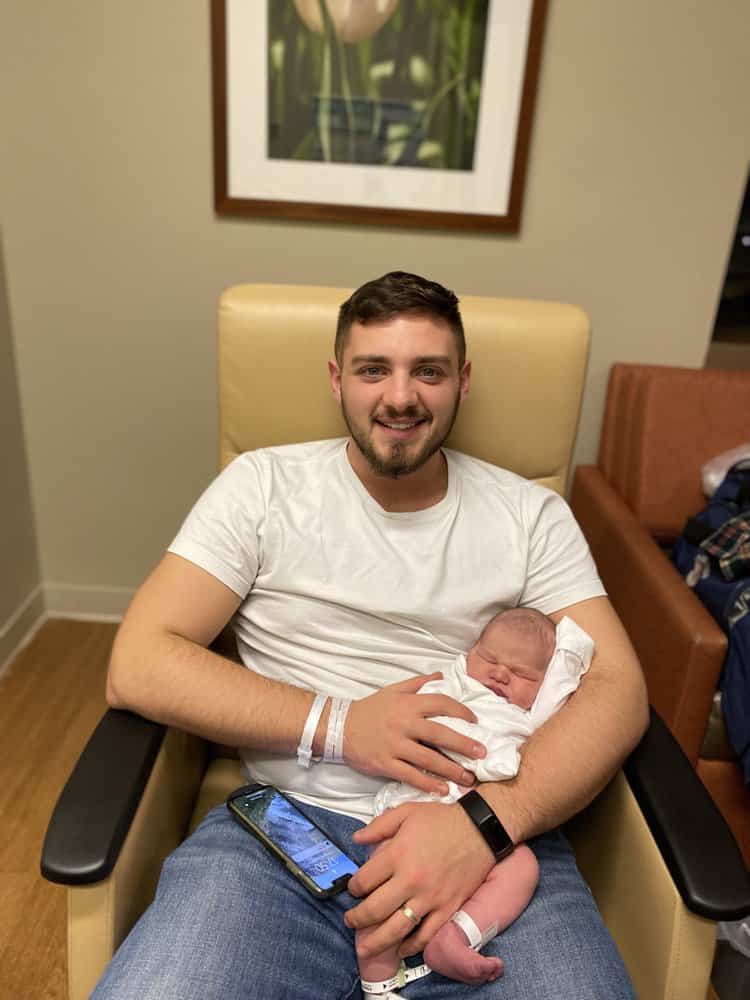 new joyful father in hospital holding his firstborn baby on his lap