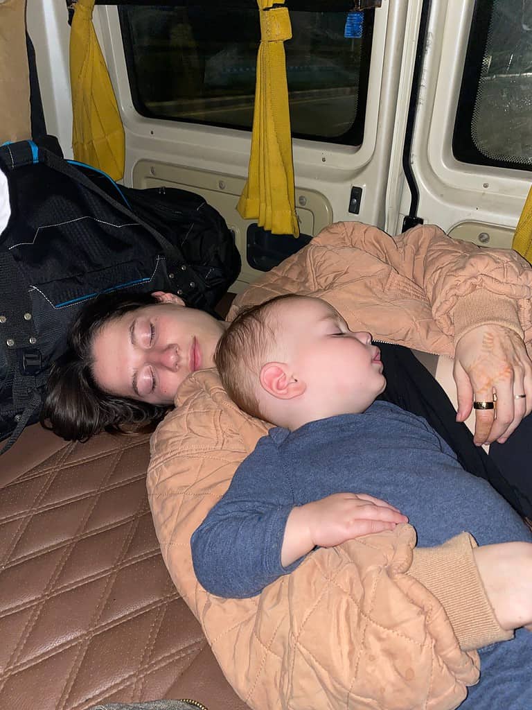 child sleeping on moms chest at night time in a van