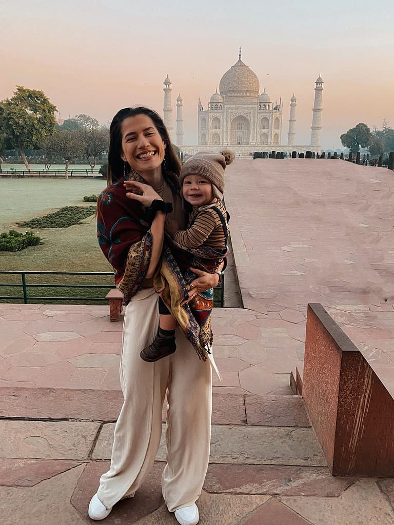 mother joyously laughing with hapy baby in her arms in front of the taj mahal