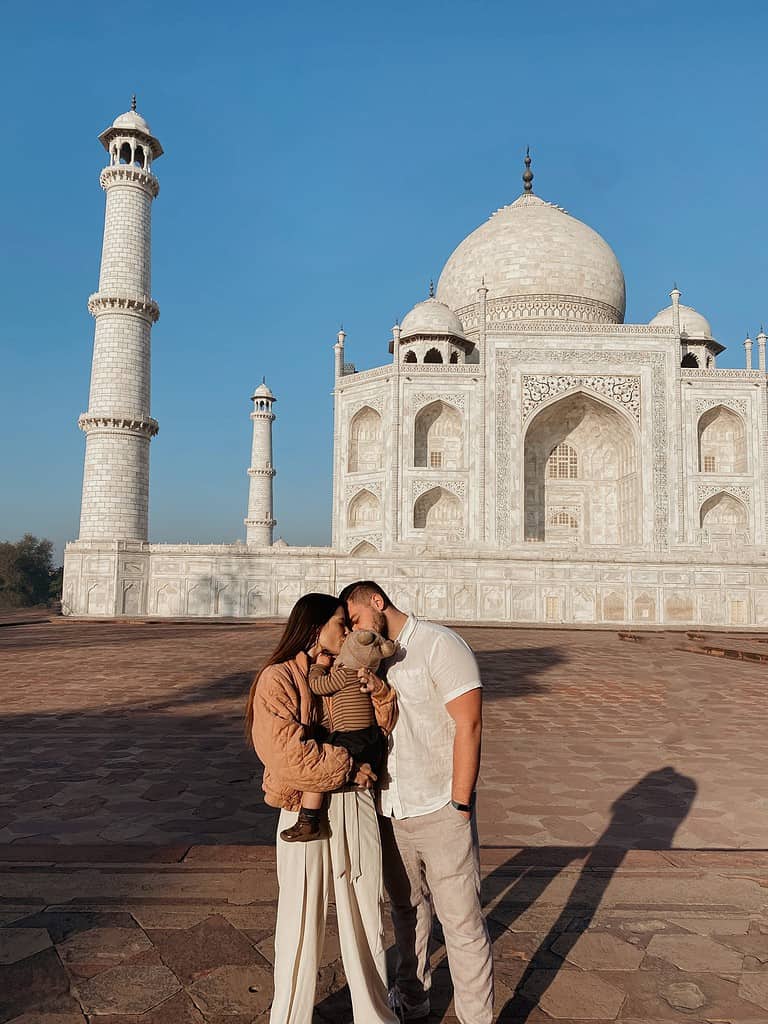 father and mother kissing baby son in front of the taj mahal