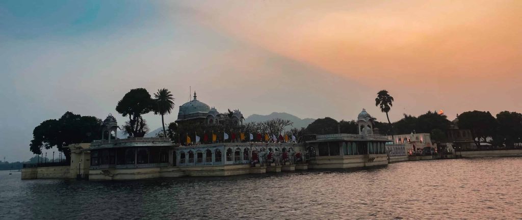 Lake view of Taj Mahal Palace on Lake Pichola during sunset with colorful orange sky