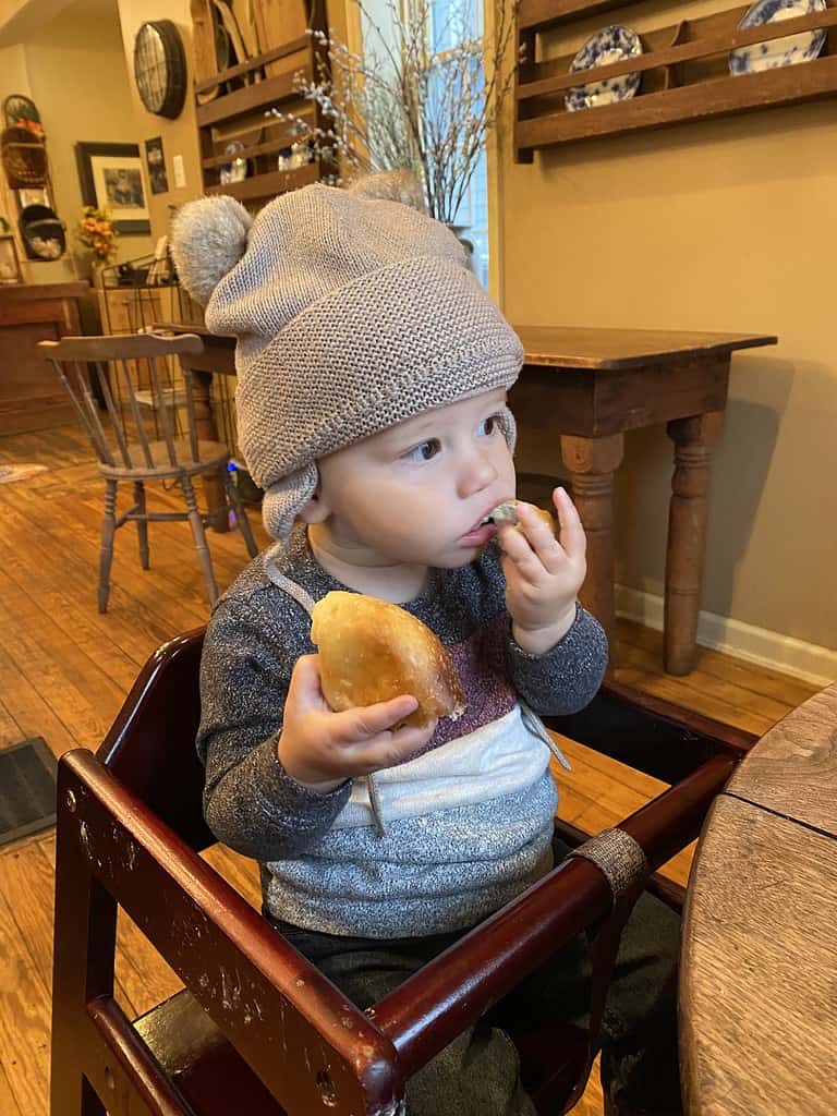 toddler in highchair eating a bagel