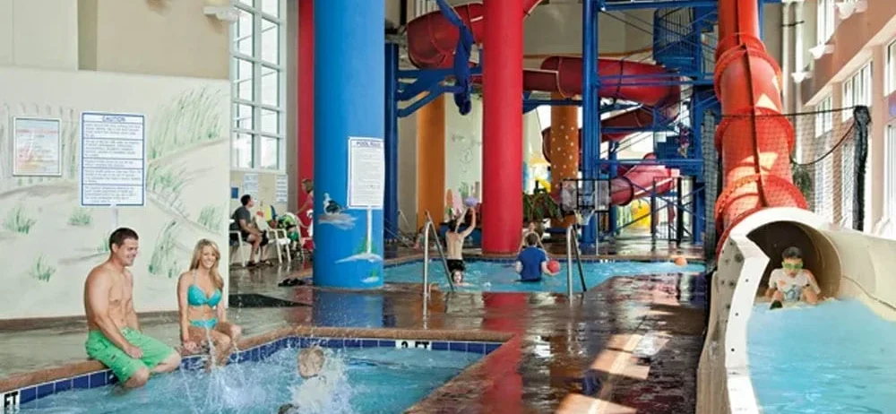 families with children playing at indoor water park with red water slide