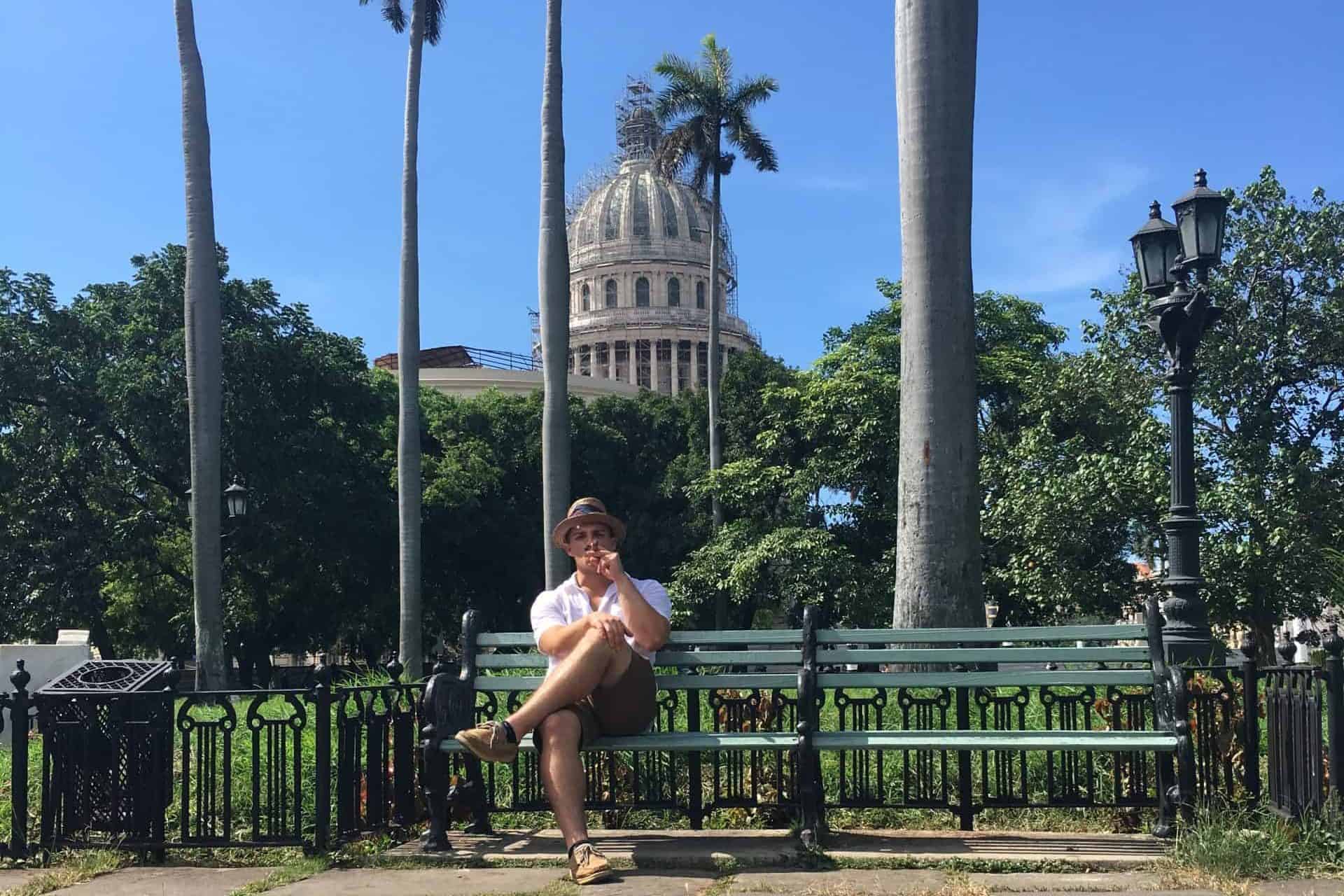 American man smoking Cuban Cigar on bench in Havana