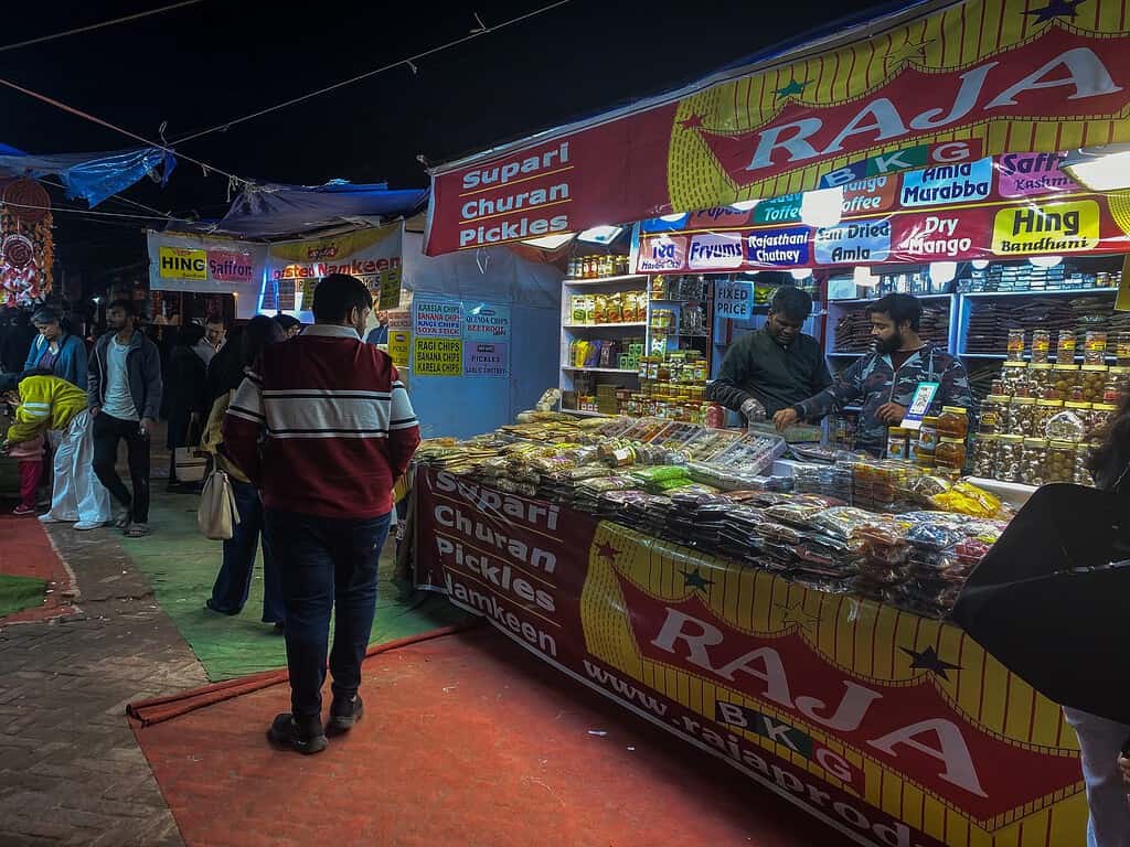 man standing in front of shop stand in the street of India at night