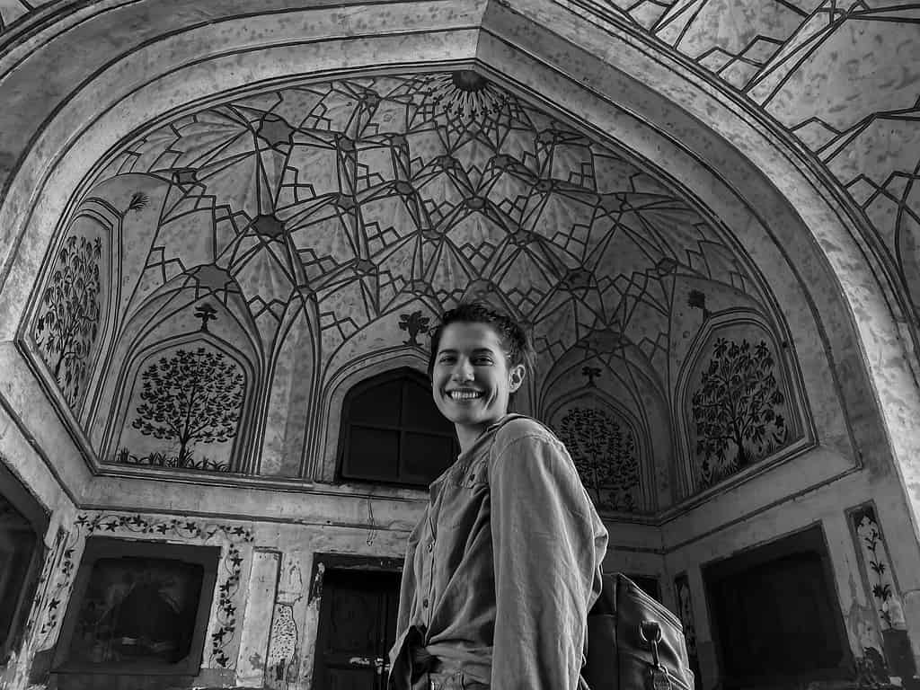 black and white picture of woman standing underneath elaborate mosaic ceiling