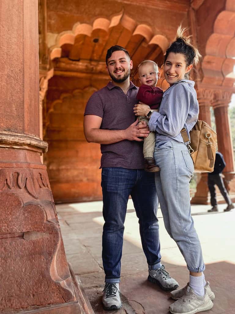 parents with toddler smiling at New Delhi's red fort