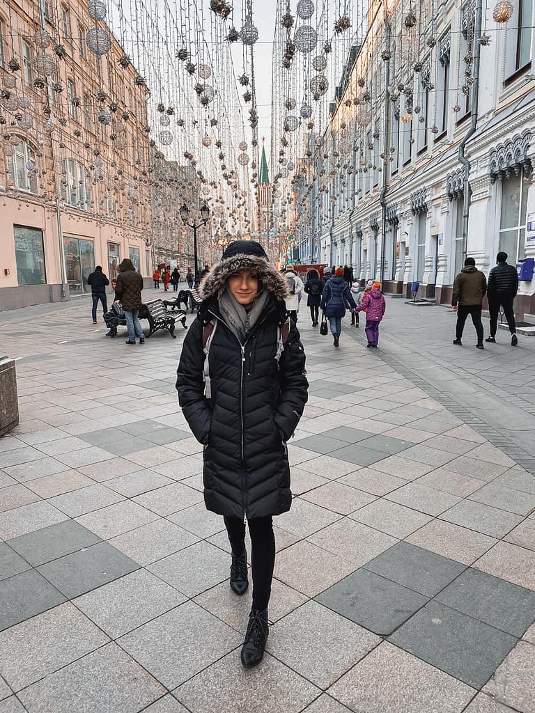 woman in black winter jacket walking down arbat street in moscow at daytime