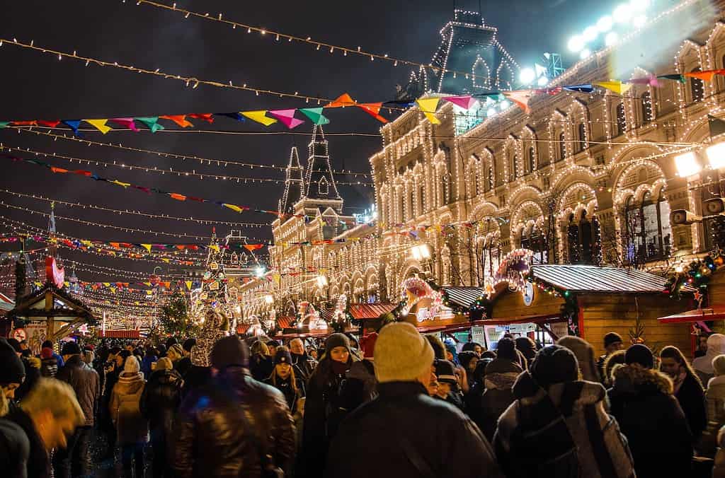 group of people walking in moscow red square at night with christmas lights everywhere