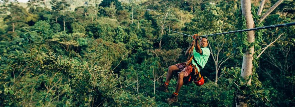 person sliding on zip line in forest