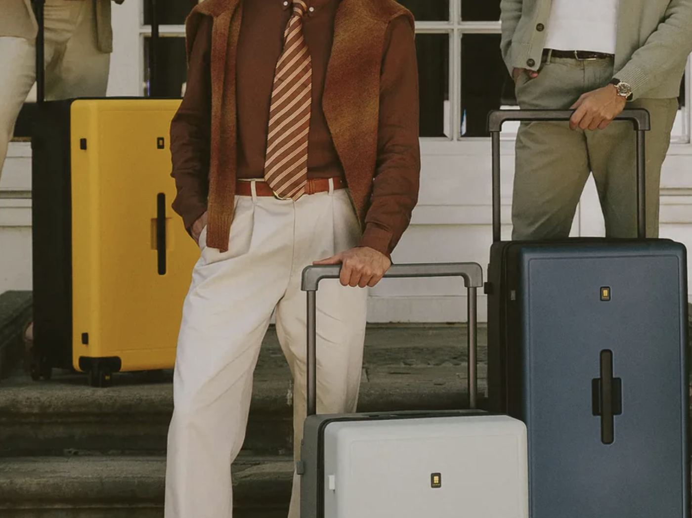 three models holding colorful suitcases