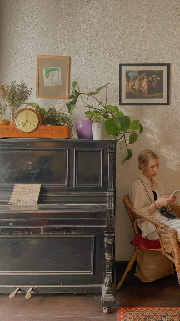 woman reading a book near a piano in a quaint cafe