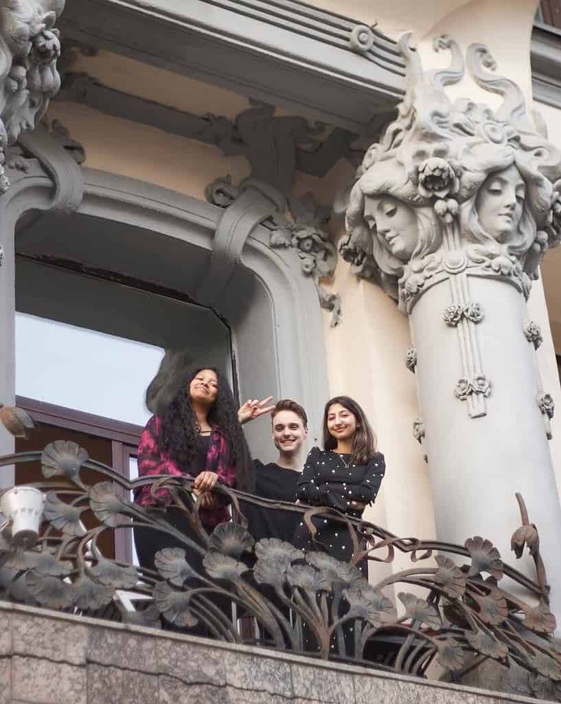 three young friends standing on balcony of an beautiful russian building