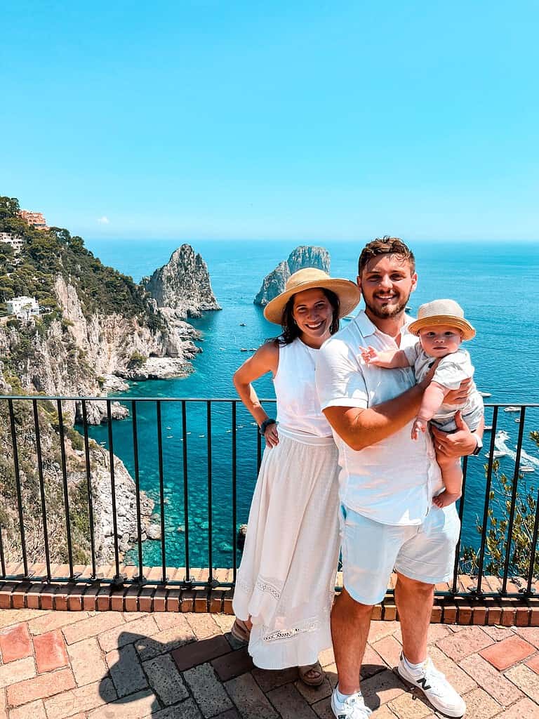 happy family with baby dressed in white overlooking the rocks in capri italy