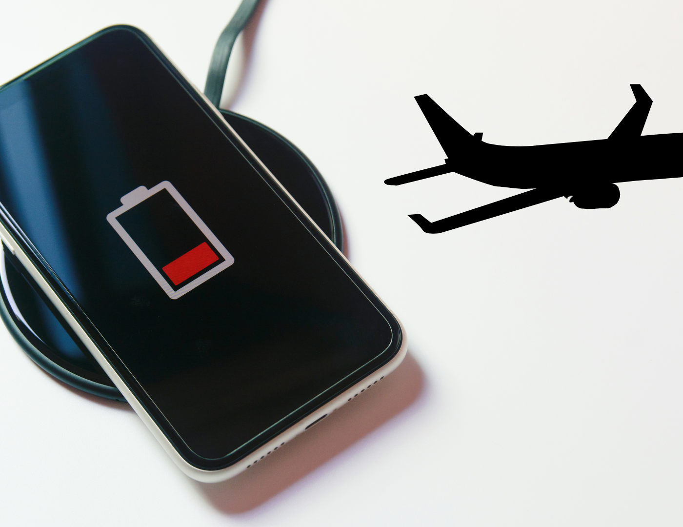 a black phone charging on a charging pad with an outline of a black plane
