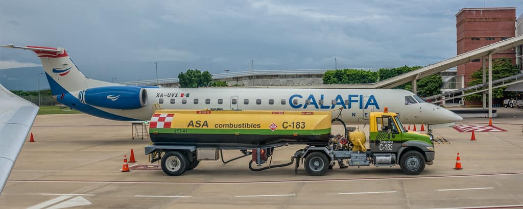 white airplane being refueled on runway