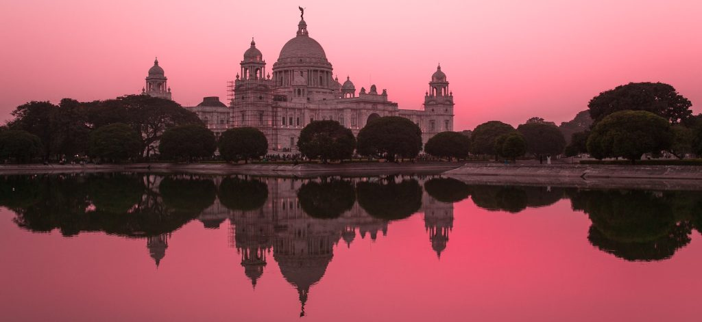 white concrete indian castle near body of pink water