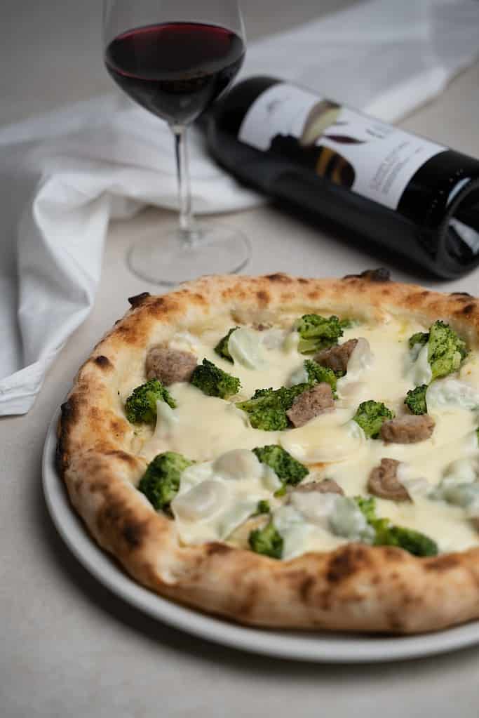 a white napolitan pizza with broccoli and cheese on a plate