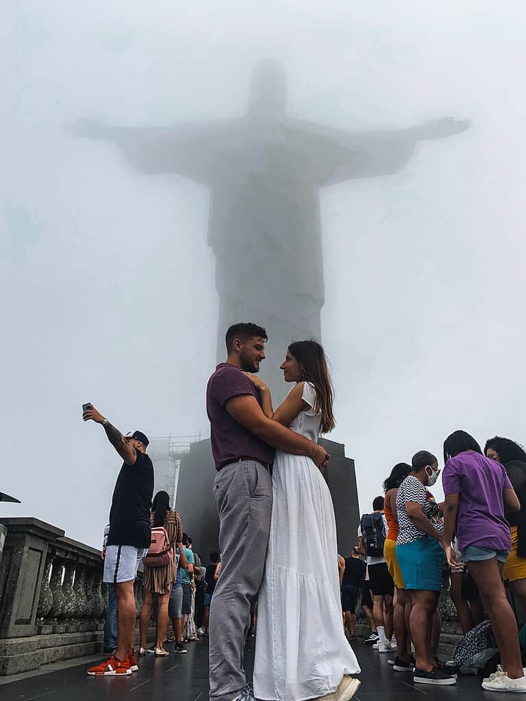 man and woman embracing on cludy day in front of christ the redeemer wonder of the world