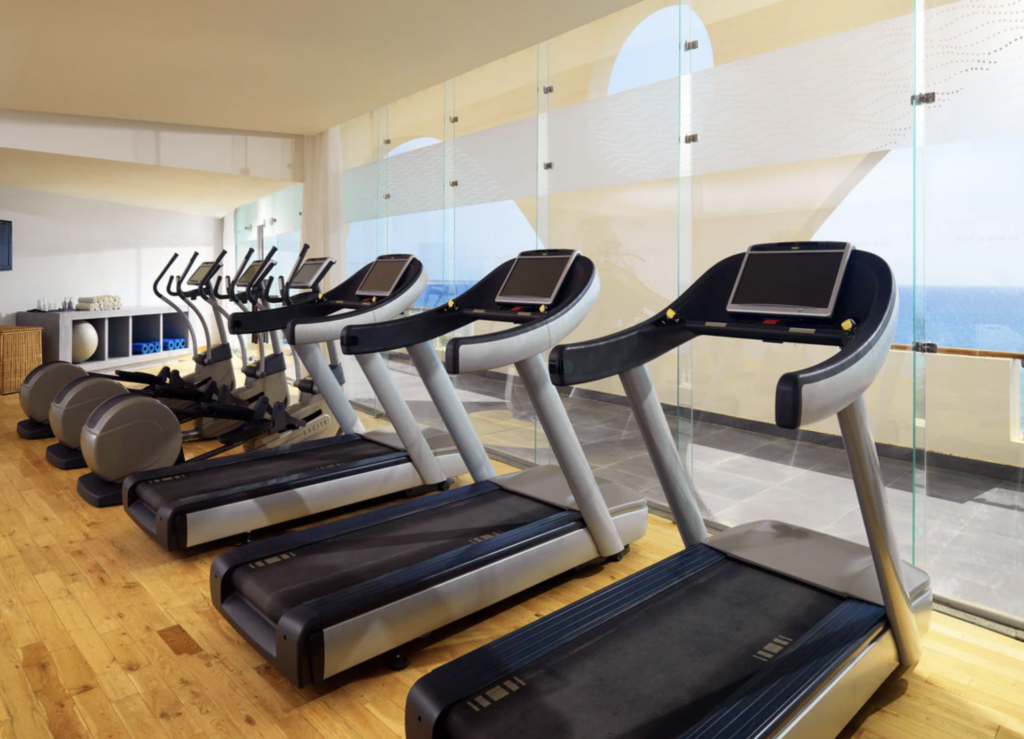 an exercise room with a row of treadmills 