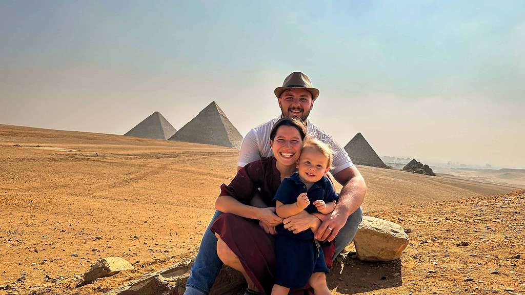 sweet family with toddler sitting in front of the pyramids of giza
