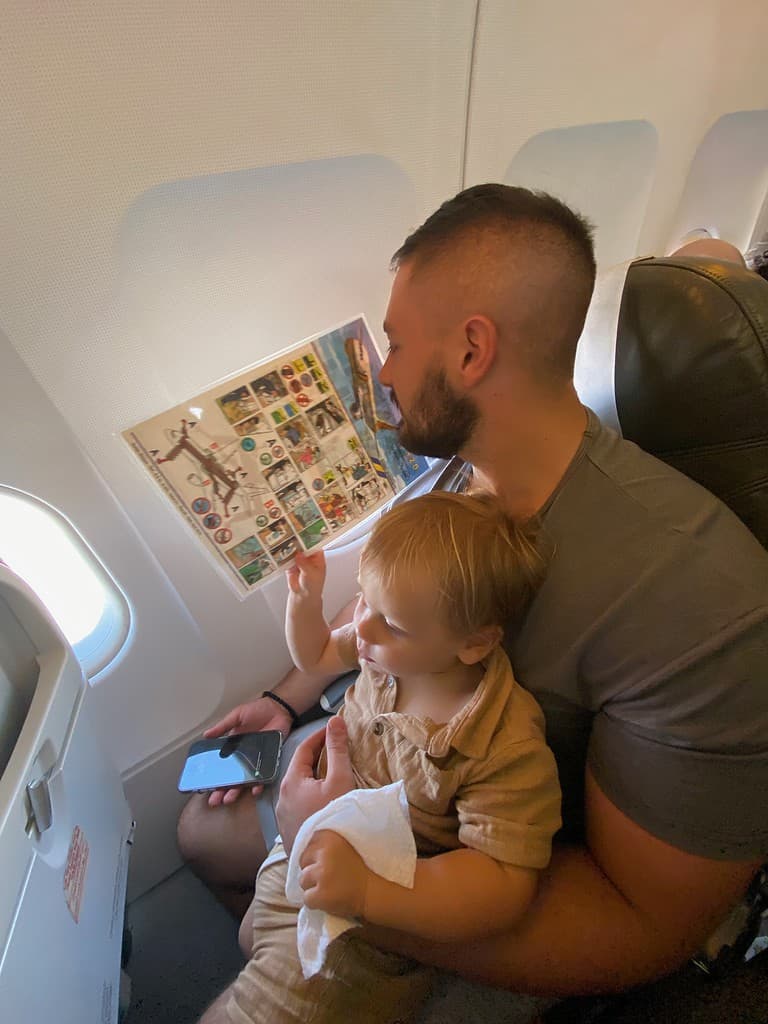 toddler son sitting on fathers lap in an airplane