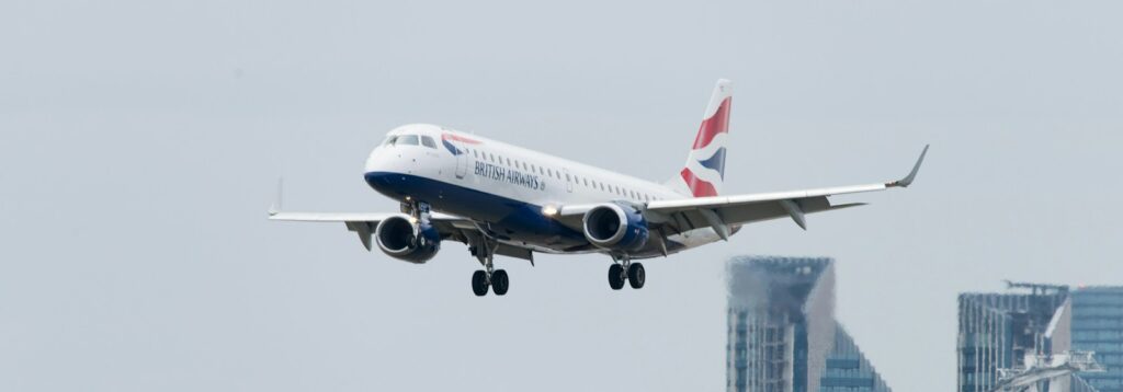 white, red, and blue british airlines airplane above buildings