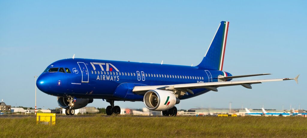 a large blue ITA airplane is on the runway