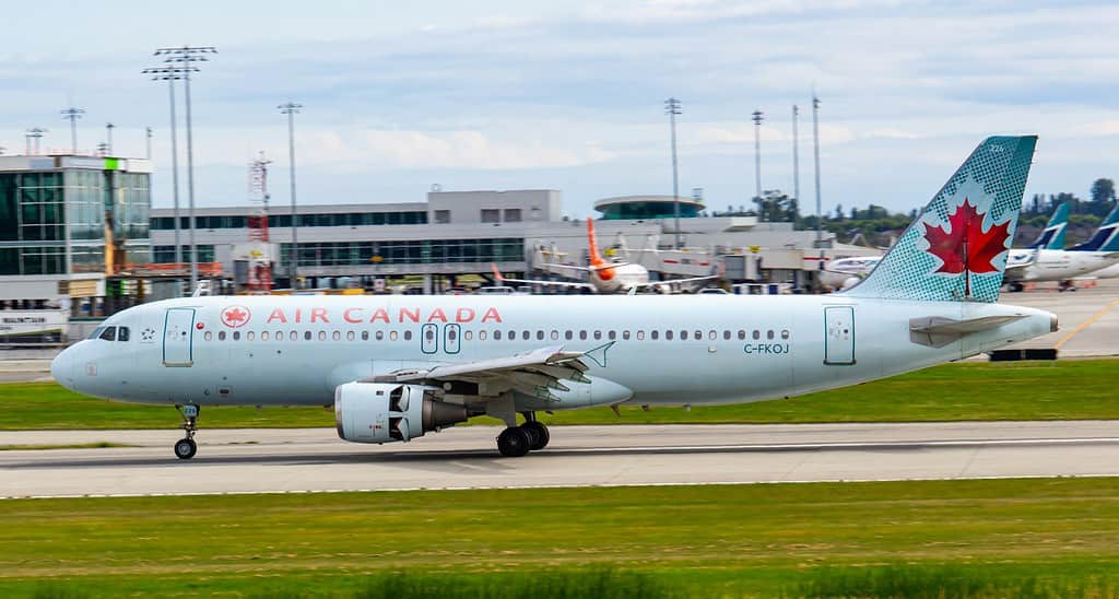 white and red passenger air canada plane on airport during daytime