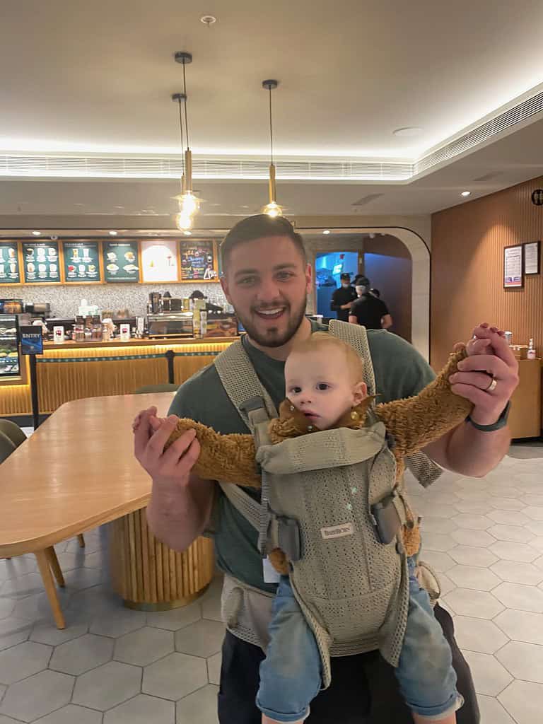 father with son strapped in carrier smiling in a starbucks store